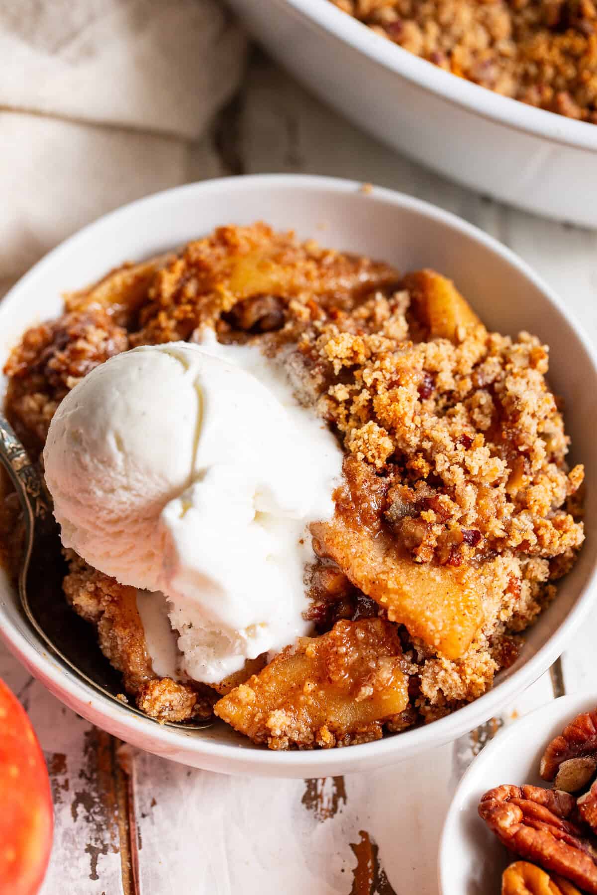 Close-up of apple crisp with tender cinnamon apples, pecan crumble and vanilla ice cream
