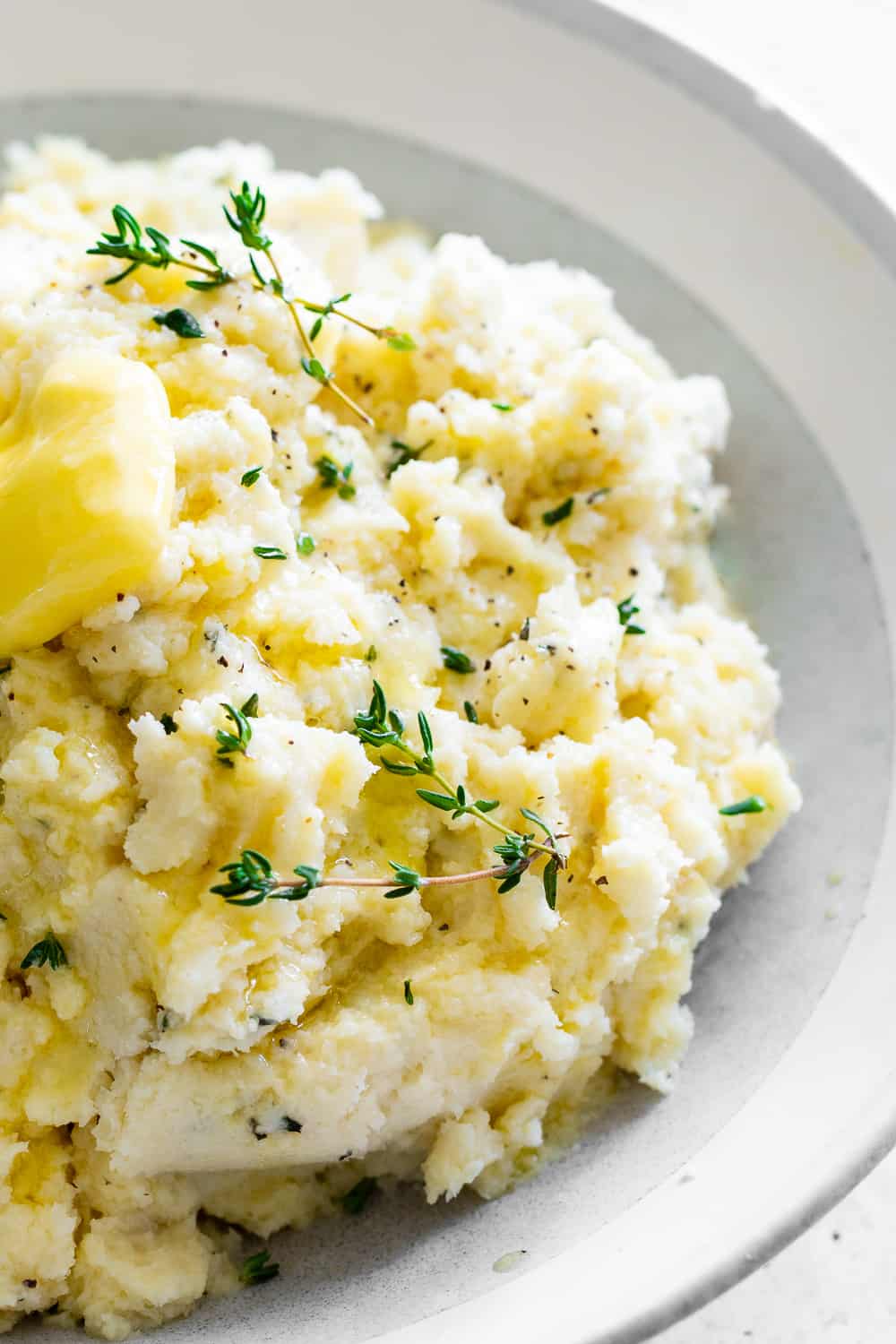 This is the simplest and most delicious recipe for mashed cauliflower (or cauliflower mashed potatoes!) Whether for a holiday dinner or anytime meal, this mashed cauliflower is super flavorful with savory garlic and fresh herbs, a side dish that will complement any main course and even steal the show! Paleo, Whole30, Keto and vegan option. #paleo #whole30 #keto #cleaneating 