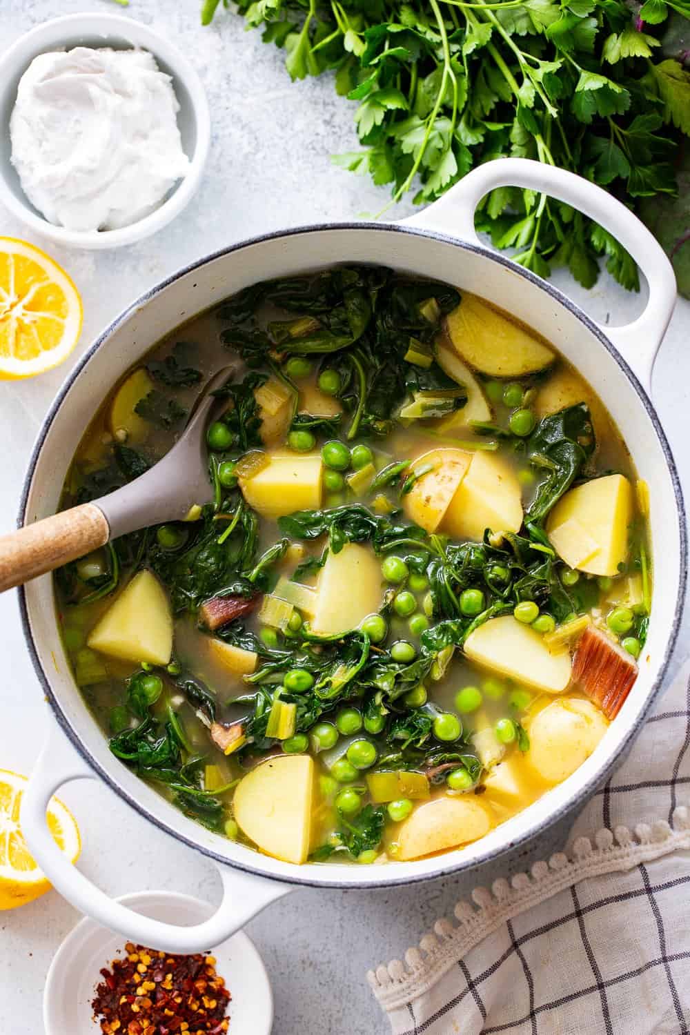 This chunky spring greens soup is full of flavor, good fats and healthy carbs. Golden potatoes, peas, spring veggies and an easy homemade dairy free sour cream make it hearty, healthy and so delicious. #paleo #whole30 #cleaneating