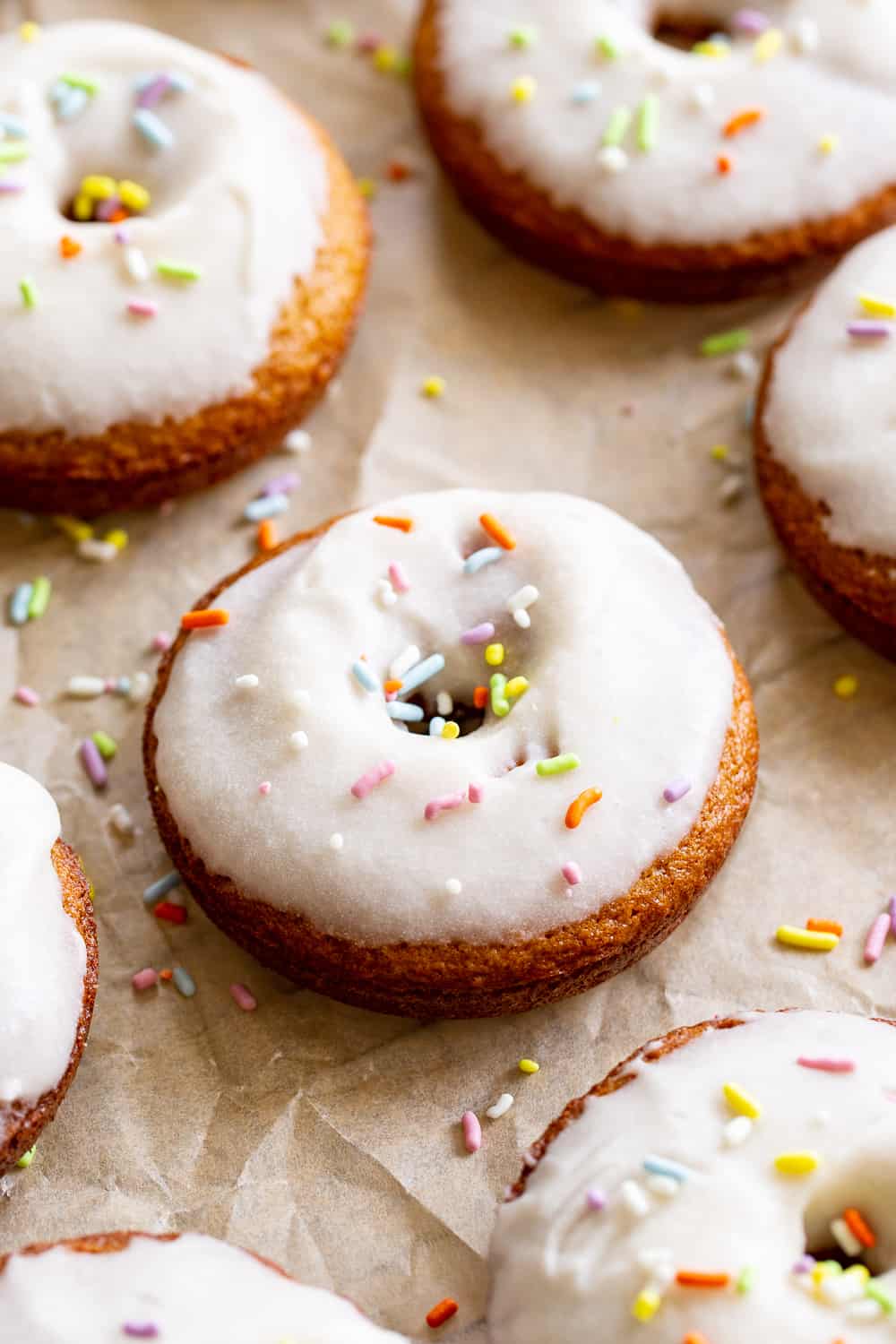 These paleo vanilla frosted donuts are a huge treat and easy to make, too! Healthy gluten free and dairy free baked donuts are dipped in a creamy vanilla frosting for a fun treat everyone will love. If you don't have a donut pan, make them into cupcakes! #paleo #cleaneating #glutenfree