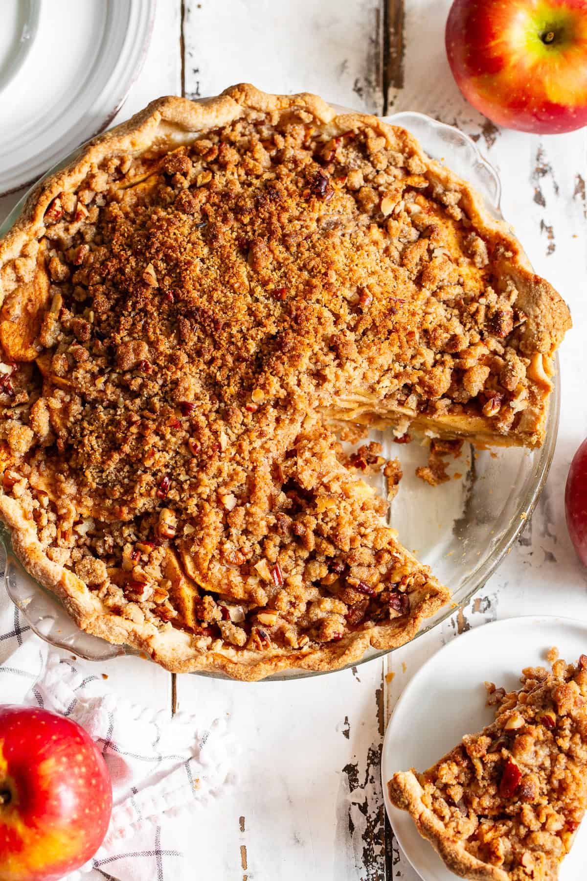 Paleo apple crumble pie with golden almond flour pecan topping and a slice removed to show the cinnamon apple filling.