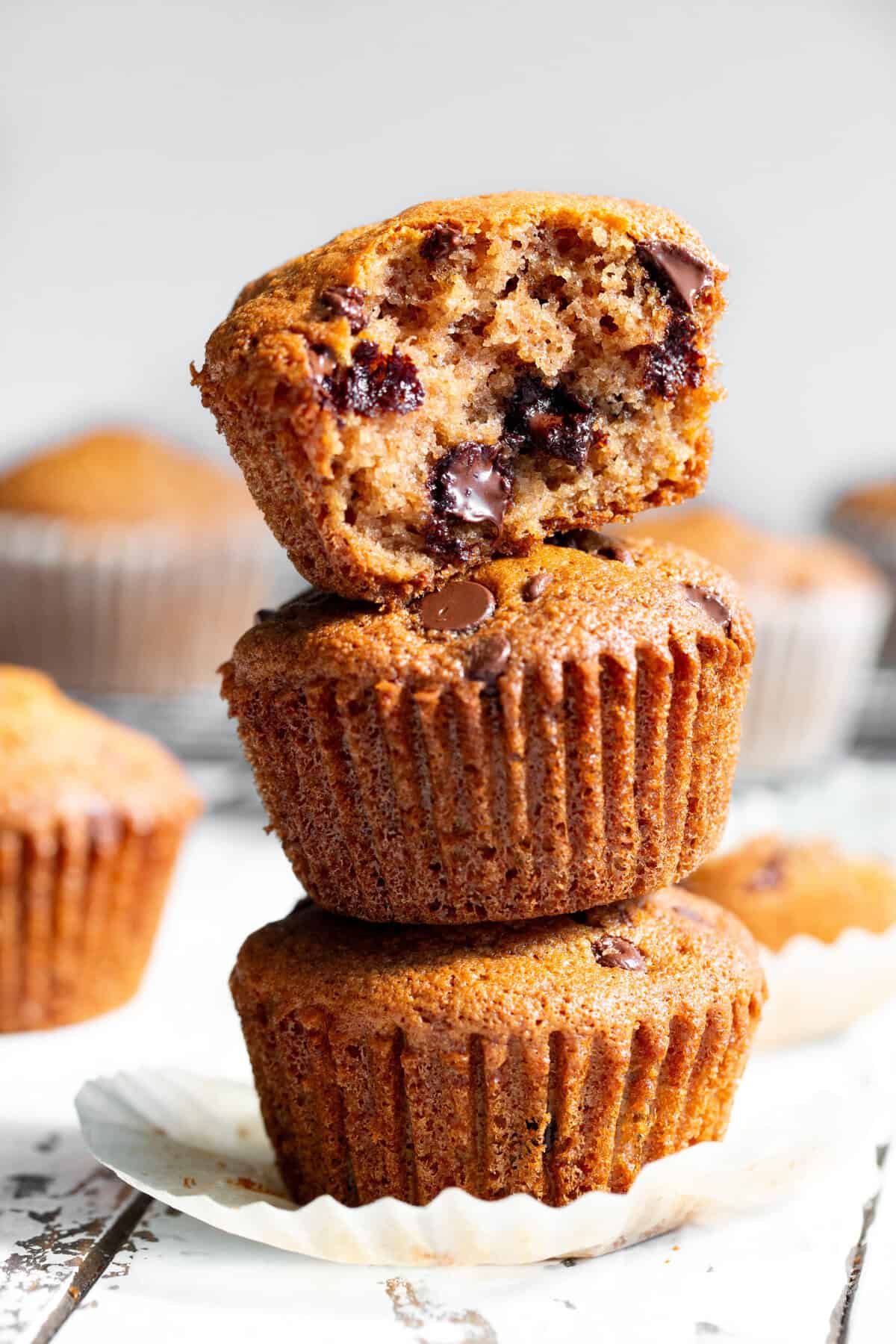 almond flour chocolate chip muffins stacked with one broken open showing moist crumb and melted chocolate chips