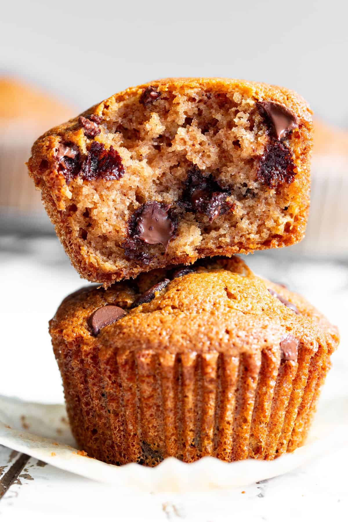almond flour chocolate chip muffins stacked with one broken open showing moist crumb and melted chocolate chips