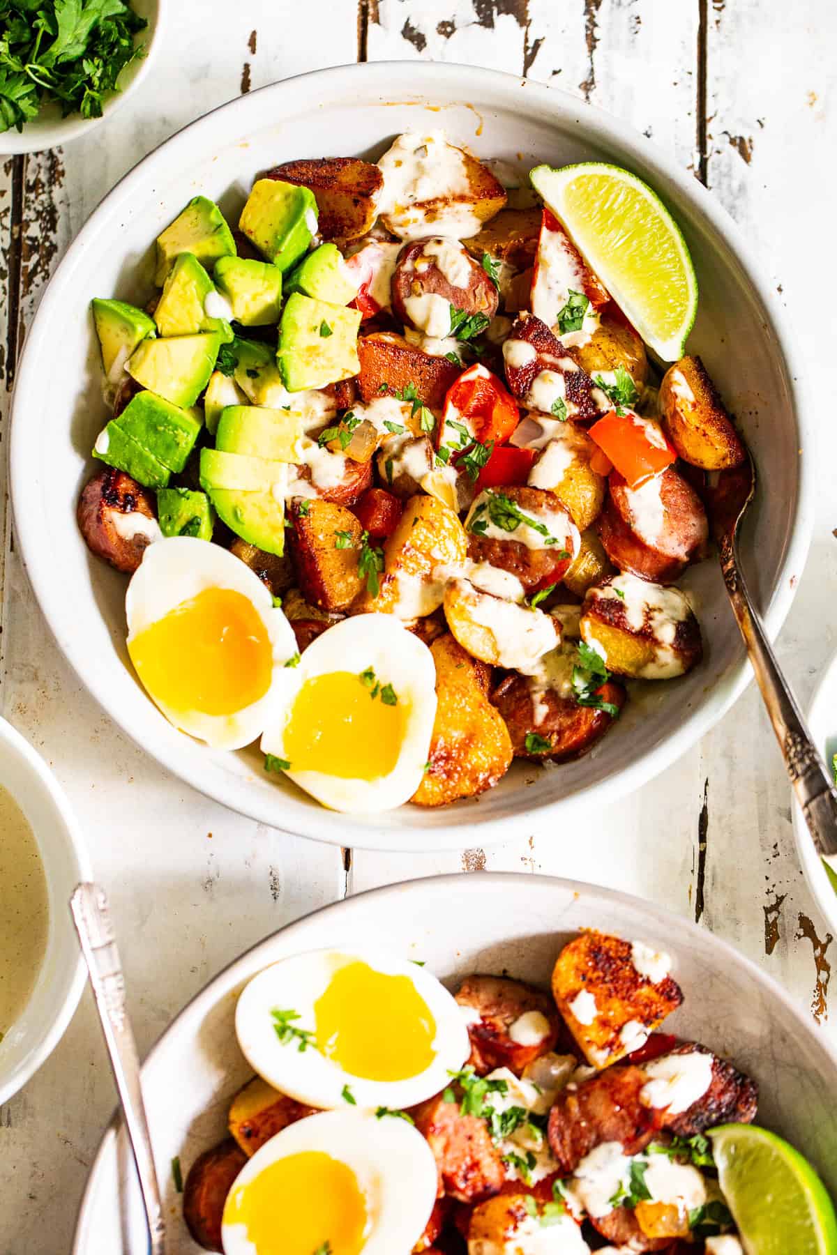High protein chicken sausage breakfast bowl with crispy potatoes, jammy eggs, avocado and salsa verde sauce.
