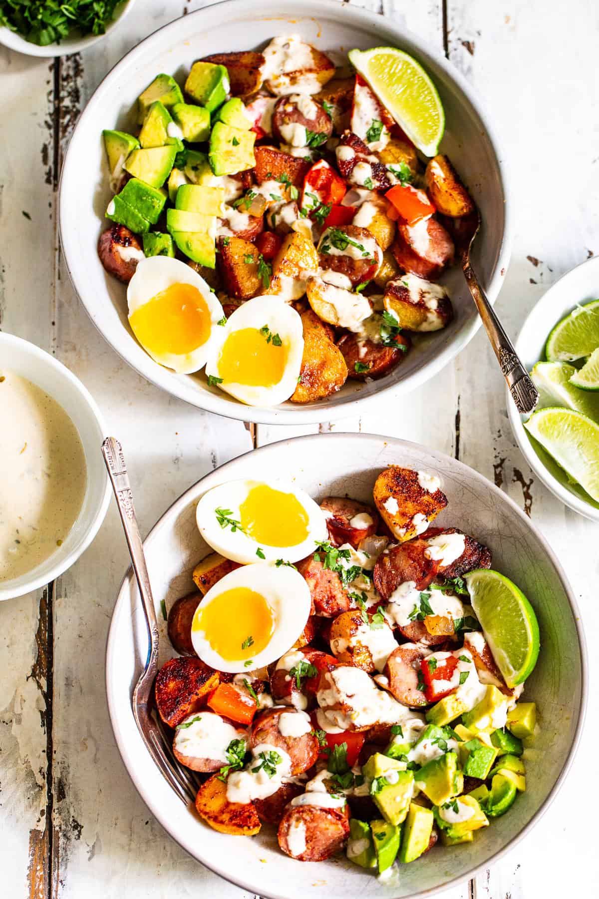High protein chicken sausage breakfast bowl with crispy potatoes, jammy eggs, avocado and salsa verde sauce.