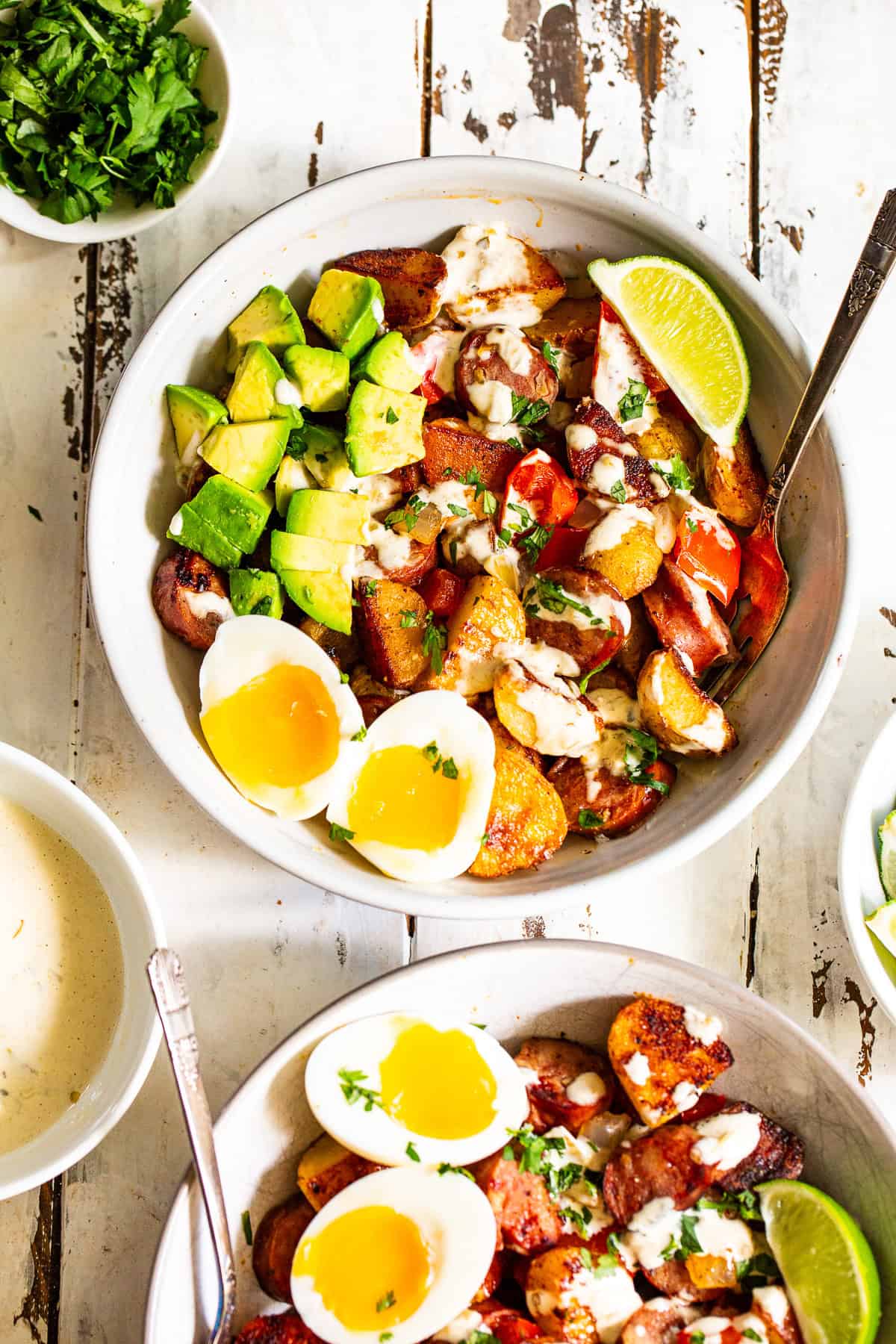 High protein chicken sausage breakfast bowl with crispy potatoes, jammy eggs, avocado and salsa verde sauce.