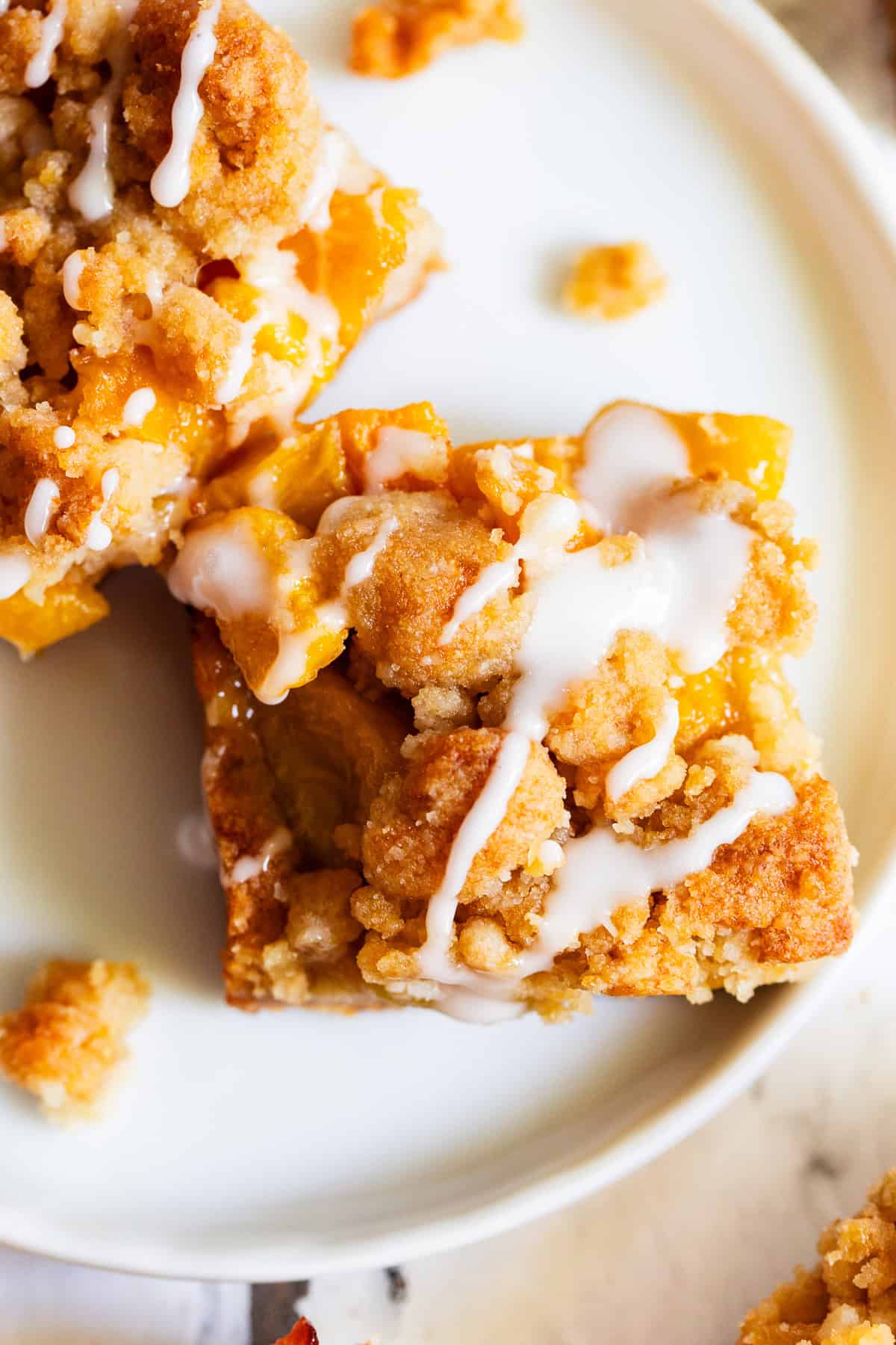 Peach crumble bar with buttery almond flour crust and golden crumb topping
