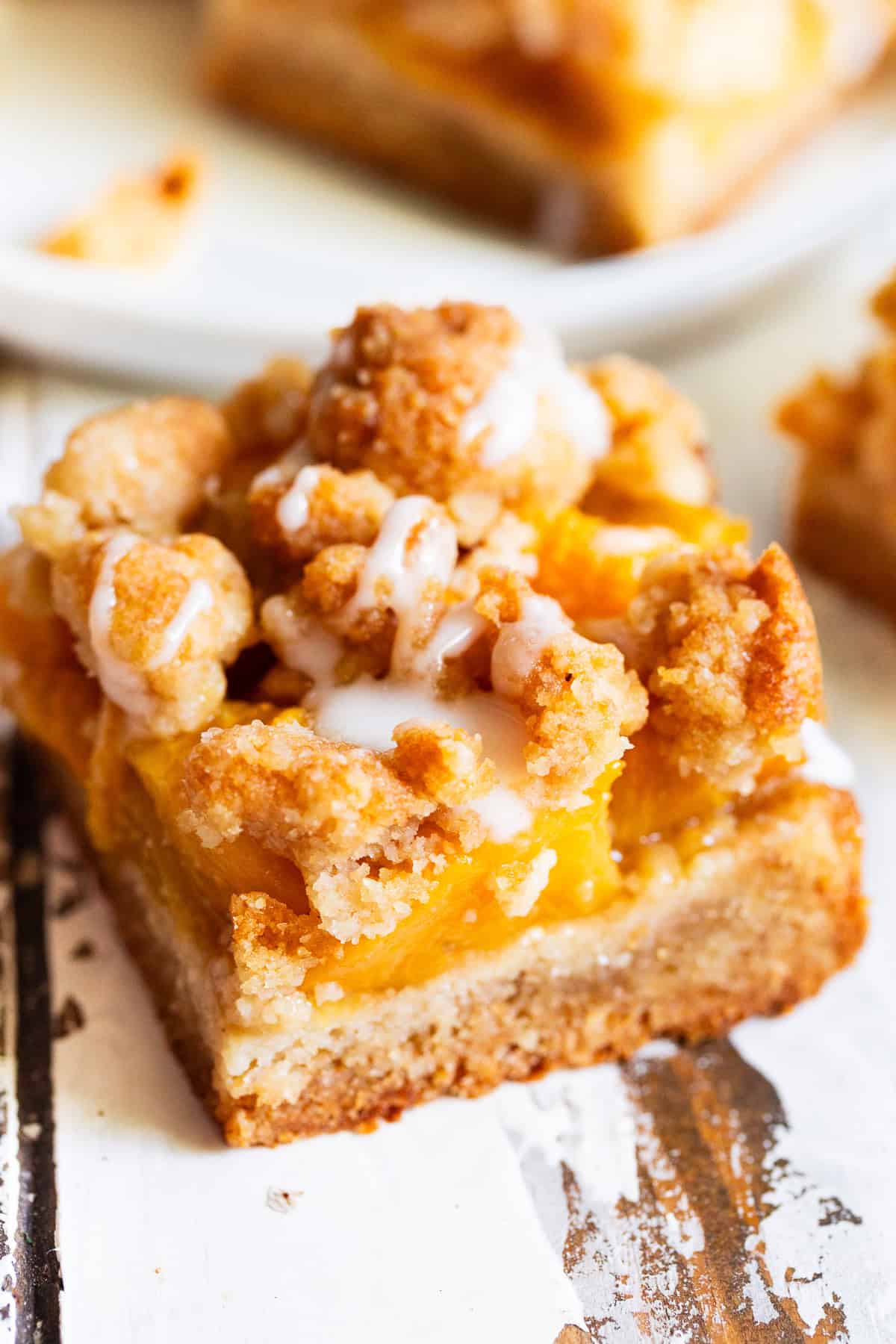 Peach crumble bar with buttery almond flour crust and golden crumb topping