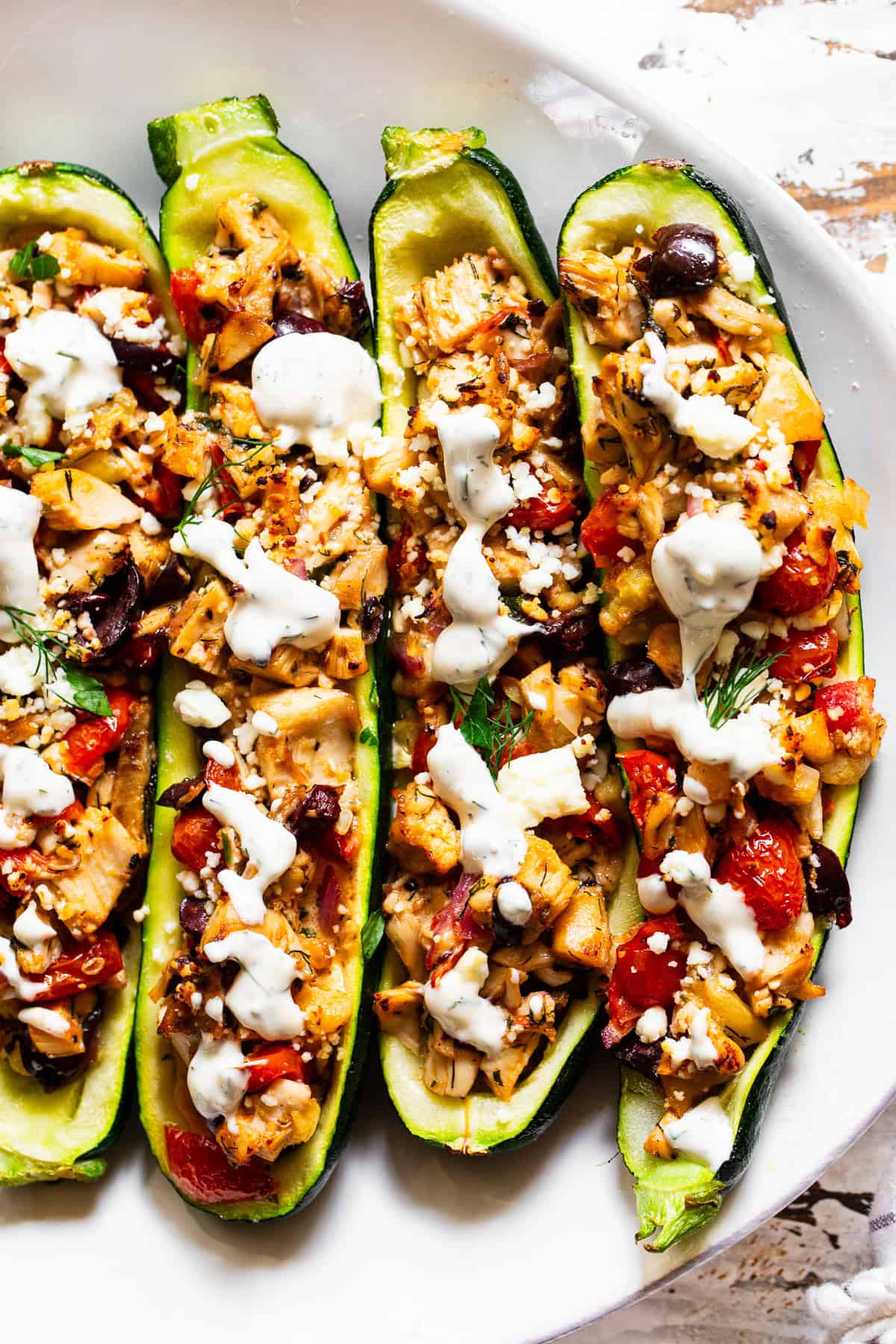 Greek chicken zucchini boats with rotisserie chicken, tomatoes, olives, feta and lemon dill sauce