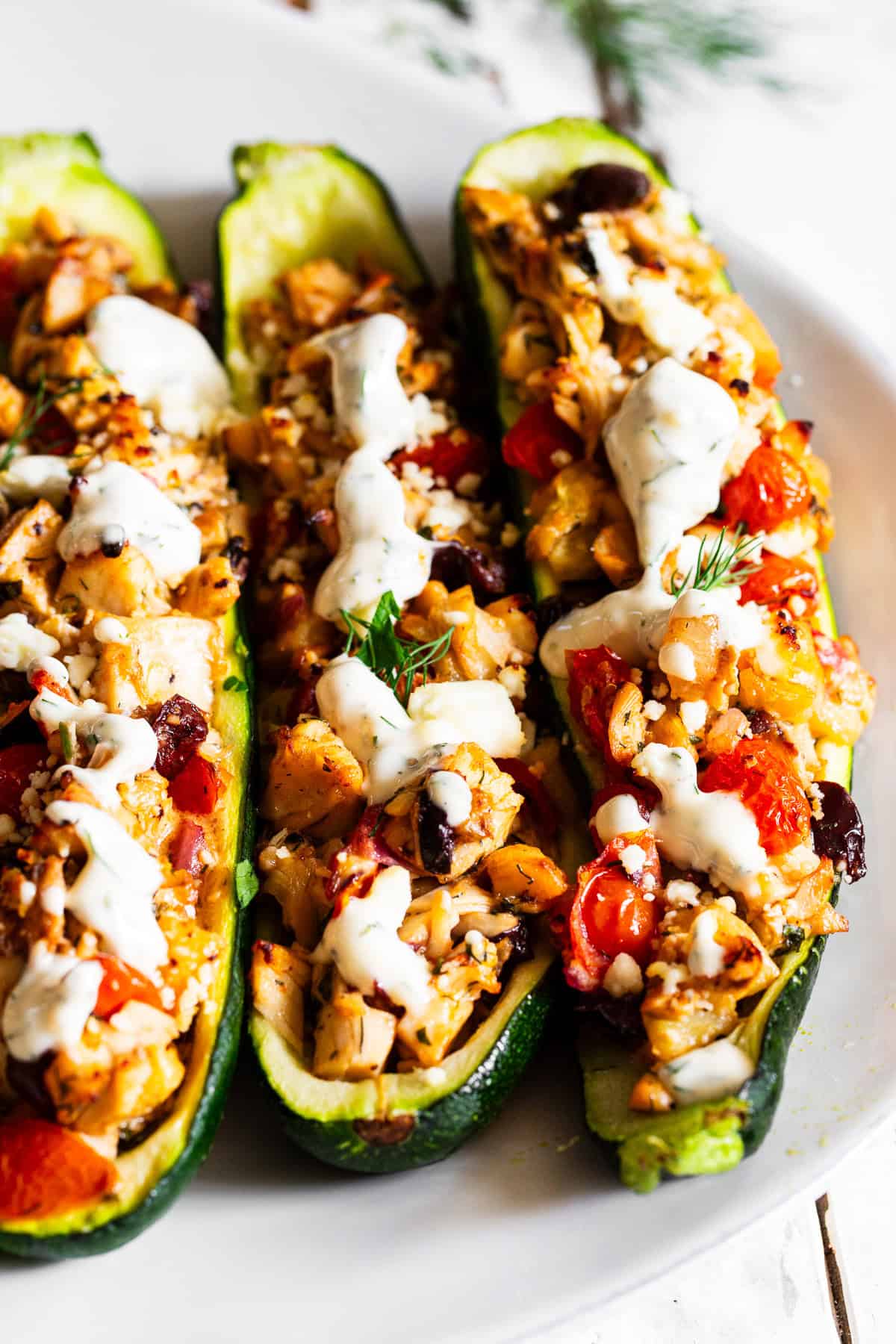 Zucchini boats with rotisserie chicken filling with tomatoes, olives, zucchini, feta and Greek seasonings and lemon dill sauce.