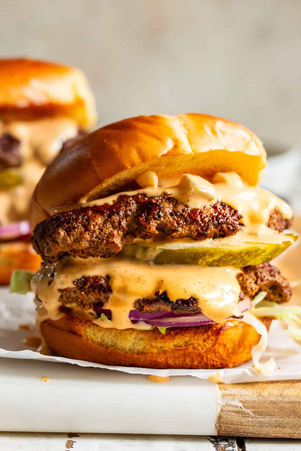Close-up of homemade smash burgers with crispy edges and creamy pickle burger sauce.