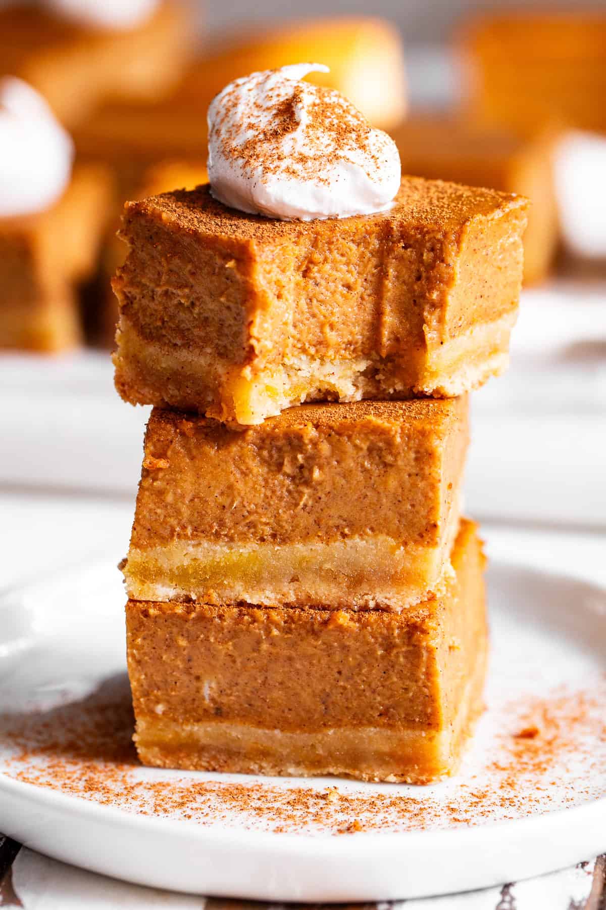 Paleo pumpkin pie bars with an almond flour crust and coconut whipped cream in a stack of 3