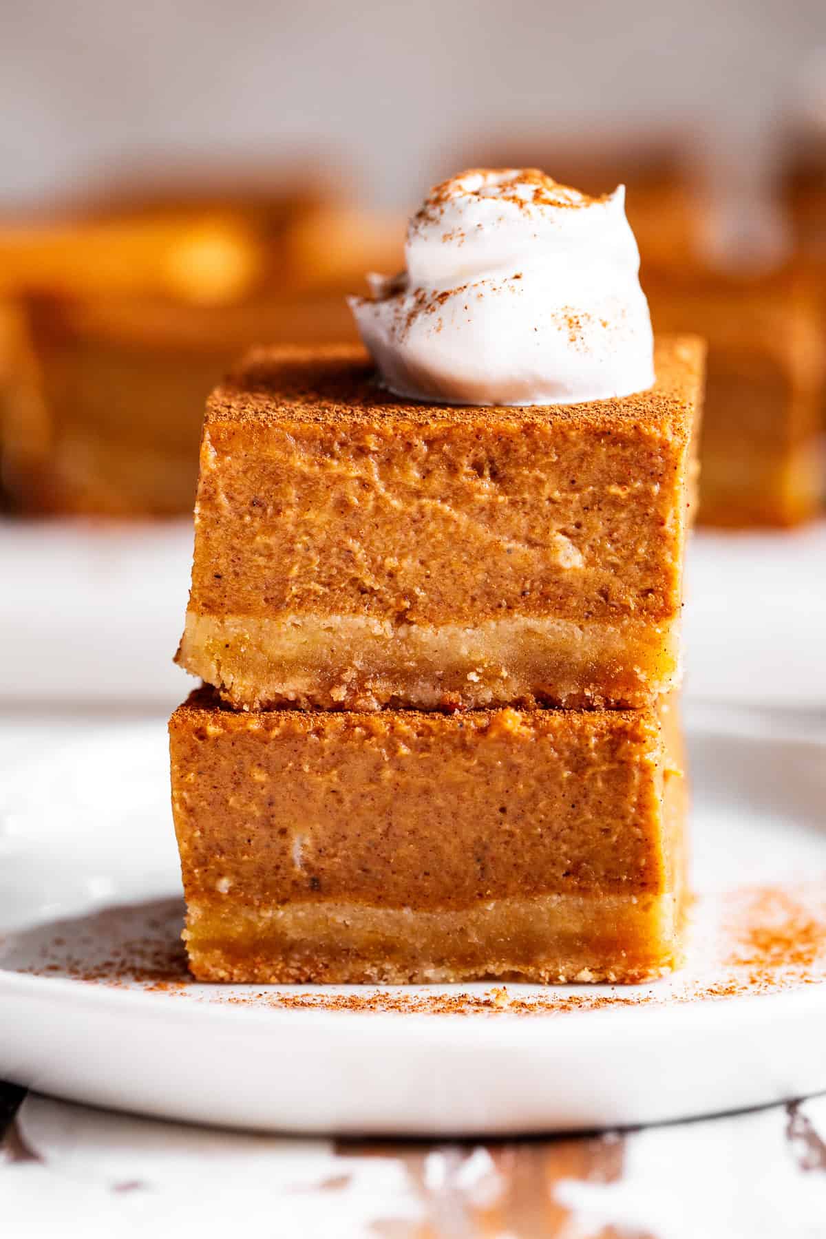 Paleo pumpkin pie bars with an almond flour crust and coconut whipped cream in a stack of 2.