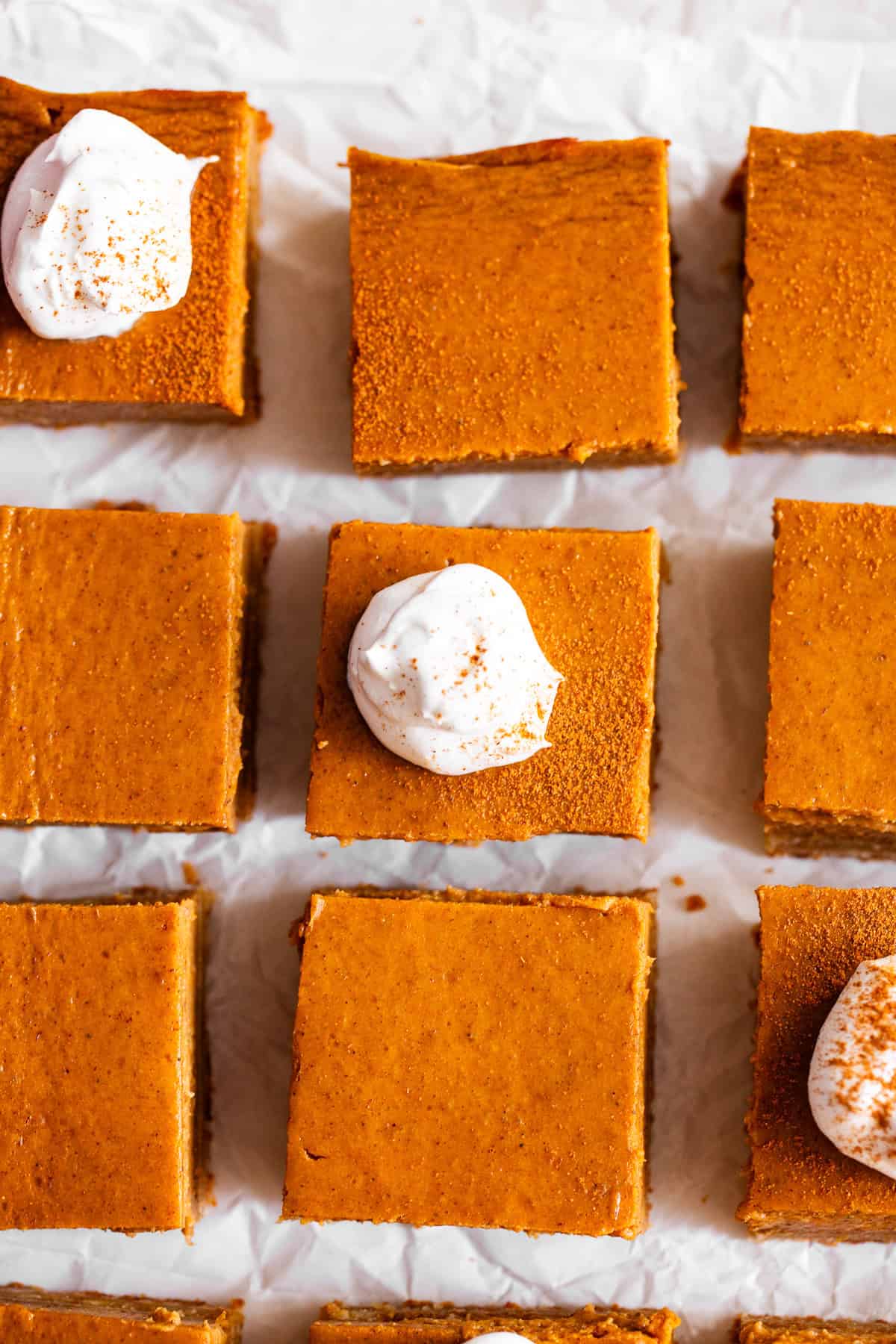 Paleo pumpkin pie bars with an almond flour crust and coconut whipped cream overhead