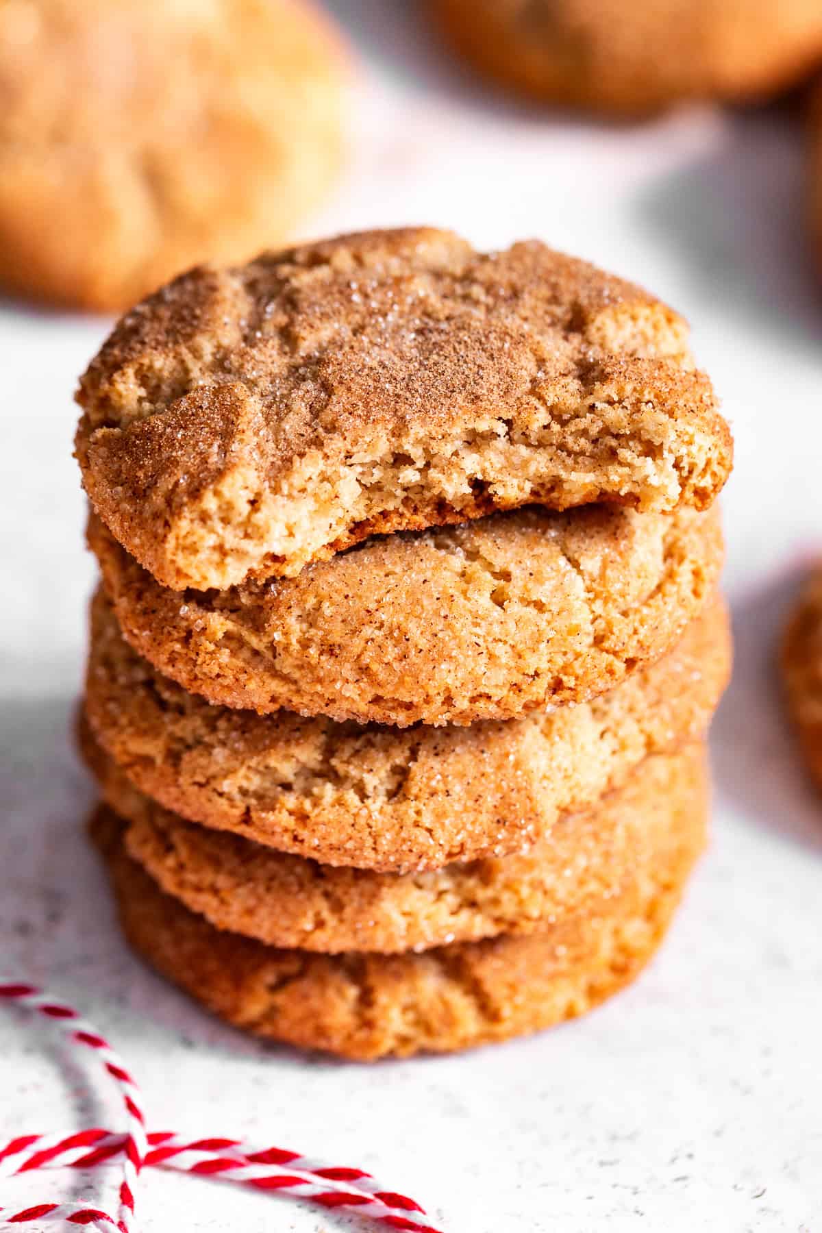 Stack of almond flour snickerdoodles with a piece missing from the top cookie, showing the center.
