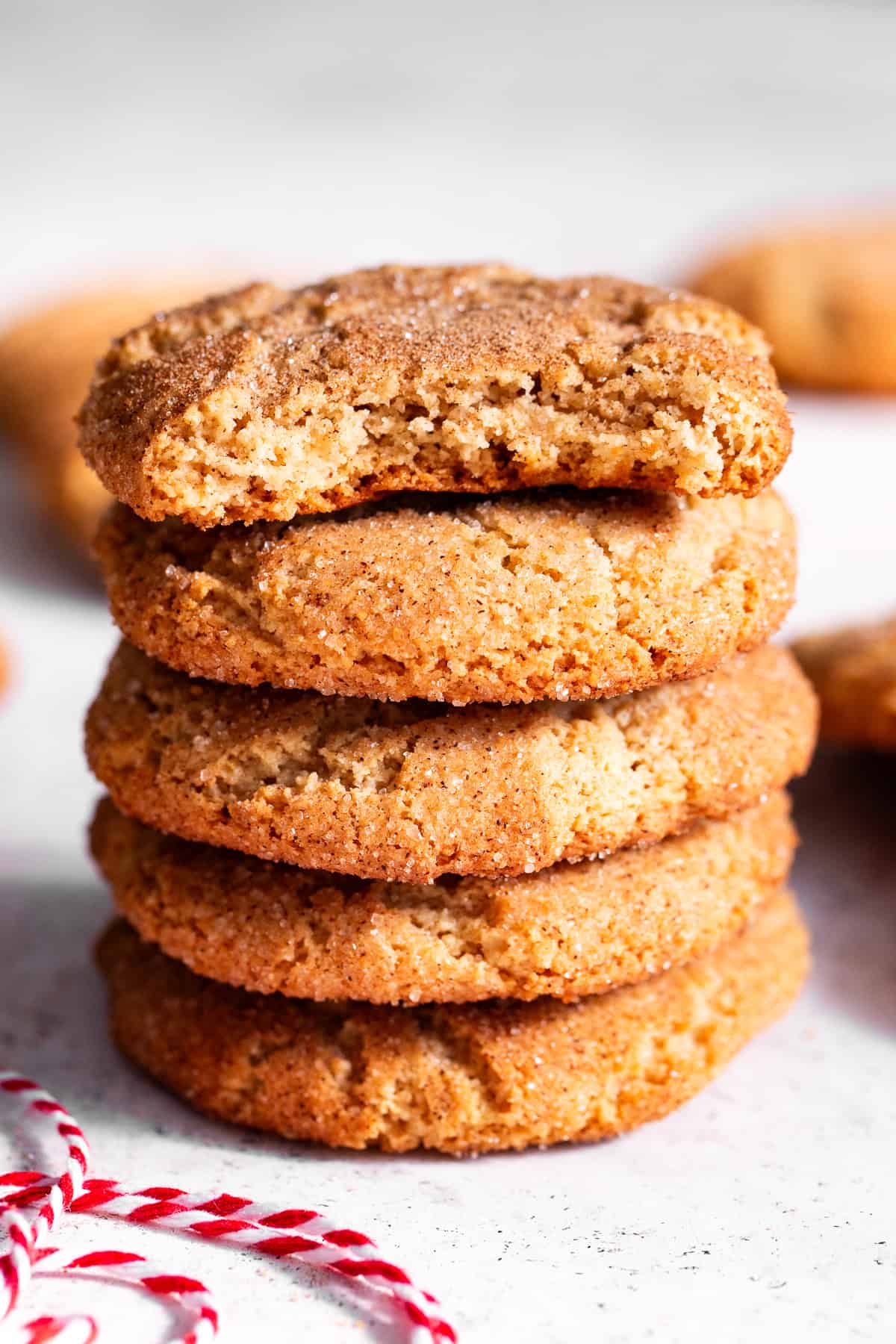 Stack of almond flour snickerdoodles with a piece missing from the top cookie, showing the center.”