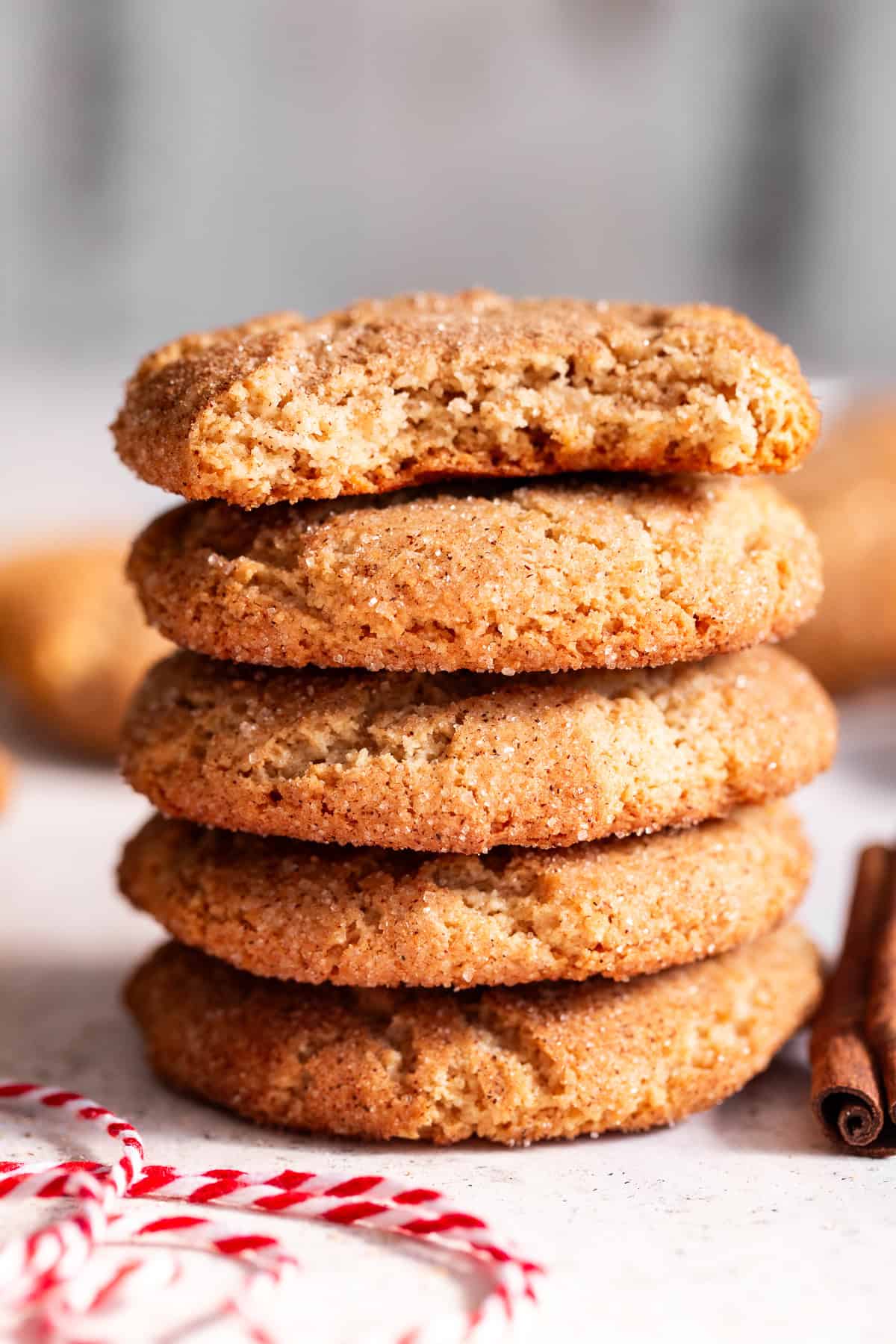 Stack of almond flour snickerdoodles with a piece missing from the top cookie, showing the center.