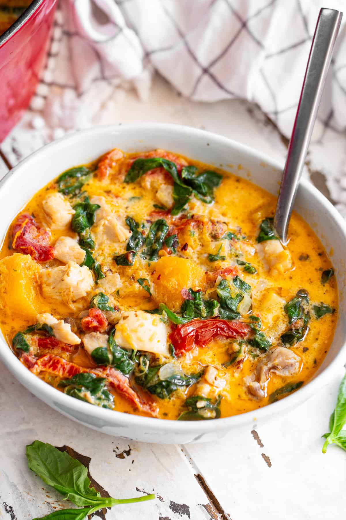 creamy tuscan chicken butternut squash soup in a white bowl