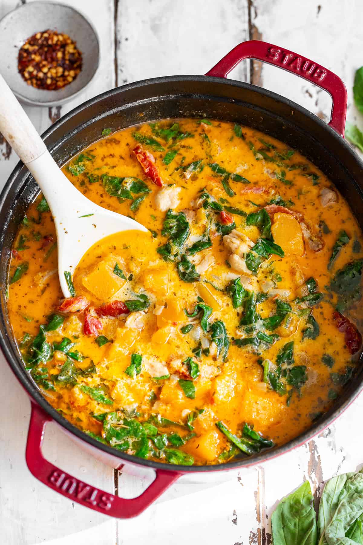 overhead shot of creamy tuscan chicken butternut squash soup in a red dutch oven with ladel